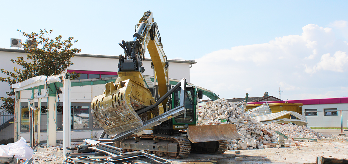<p>Mitte März begannen die Abrissarbeiten der 1985 erstellten Produktionshalle, welche zuletzt den Formenbau und die technische Abteilung beherbergte. Auf dem neu gewonnen Gelände werden moderne Arbeitsflächen für Produktion und Verwaltung entstehen.</p><p>Nachdem die Räumlichkeiten in den letzten Jahren kaum mehr Platz für neue Mitarbeiter und die Erweiterung des Maschinenparks boten, stehen im neuen Gebäude nach Fertigstellung zusätzliche, neue Büroarbeitsplätze sowie ein weiterer Besprechungsraum zur Verfügung. Das Technikum wird vergrößert und integriert.</p><p>Das neue Gebäude wird sich nahtlos an die nebenstehende, zentrale Produktionshalle anschließen, so dass Transportwege über den Außenbereich entfallen. Von der ursprünglichen sowie nachhaltigeren Idee der Erweiterung der Halle, musste die Geschäftsführung aufgrund von Baubestimmungen Abstand nehmen.</p><p class="ql-align-justify">Die Baumaßnahme folgt auf den Neubau des Hauptverwaltungsgebäudes und die Modernisierung der zentralen Produktionshalle in 2016, durch welche Bürokapazitäten erweitert und neue Sozialräume für die Produktionsmitarbeiter geschaffen wurden und markiert einen weiteren Meilenstein in der langfristigen Wachstumsstrategie von <strong>em</strong>technik.</p>